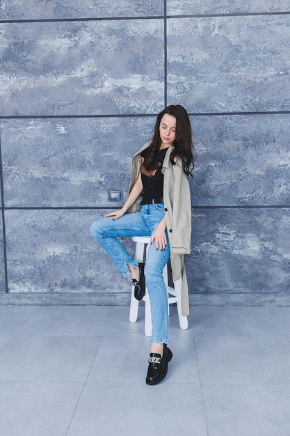 Beautiful woman with slender legs in jeans and fashionable outerwear with a raincoat stylish leather shoes Women's image in spring style