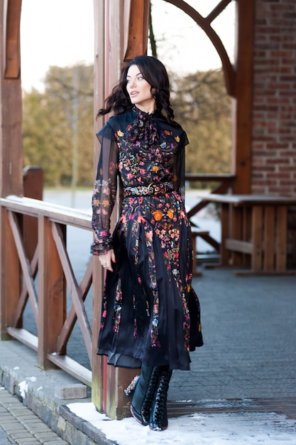 Beautiful woman with smile in dress near wooden handrail