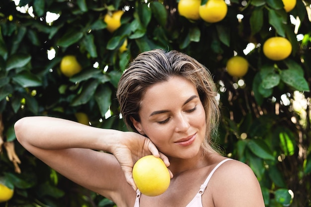 Красивая женщина с гладкой кожей с фруктами лимона в руках