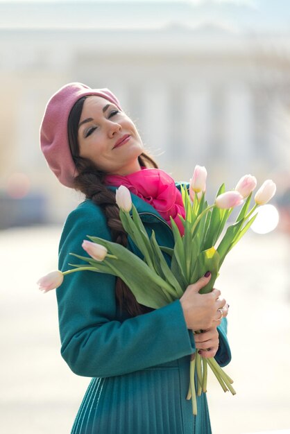 Beautiful woman with spring tulips flowers bouquet at city street happy portrait of girl smiling
