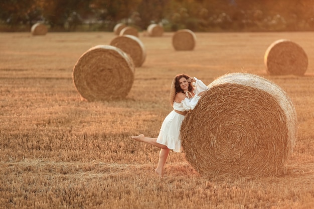 Beautiful woman with straw bales in summer