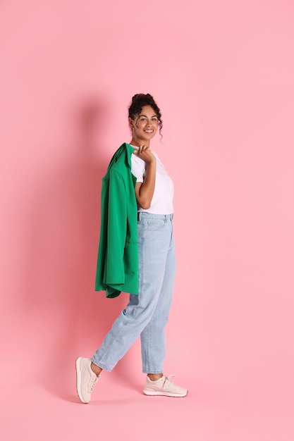 Beautiful woman with stylish jacket on pink background