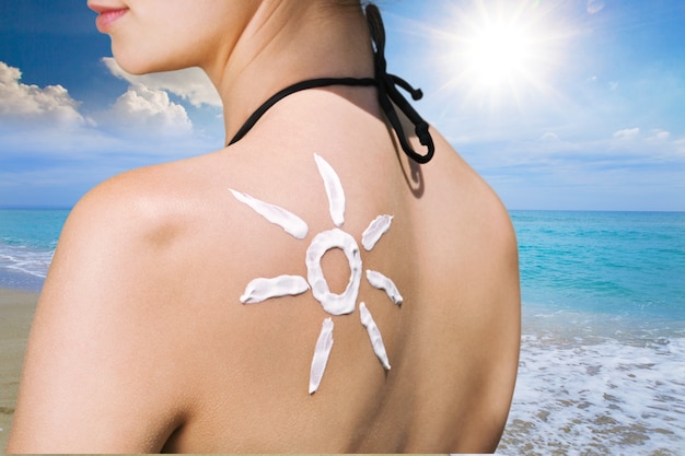 Beautiful Woman with Sunscreen Solar Cream over ocean background. Sun Tanning.