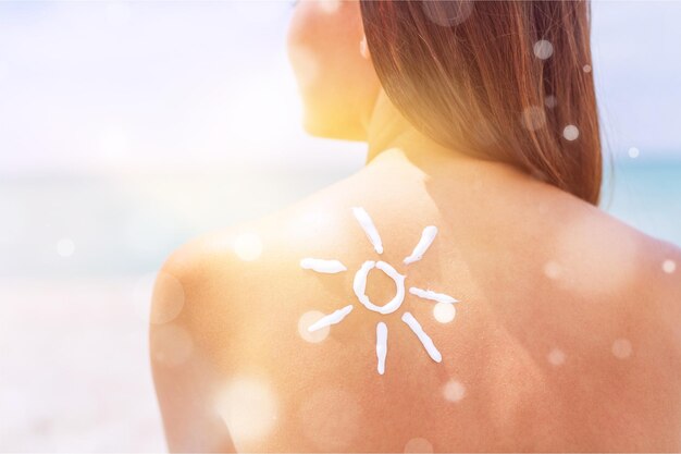 Photo beautiful woman with sunscreen solar cream over ocean background. sun tanning.