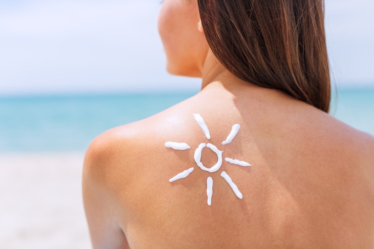 Photo beautiful woman with sunscreen solar cream over ocean background. sun tanning.