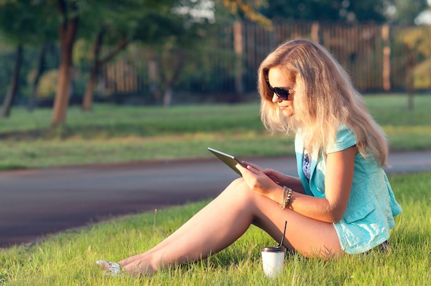 Beautiful woman with tablet in his hands. Woman relaxing on the nature. Beautiful toning.