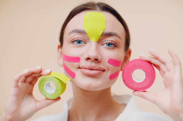 Beautiful woman with tape in hands for face lifting treatment procedure face building concept