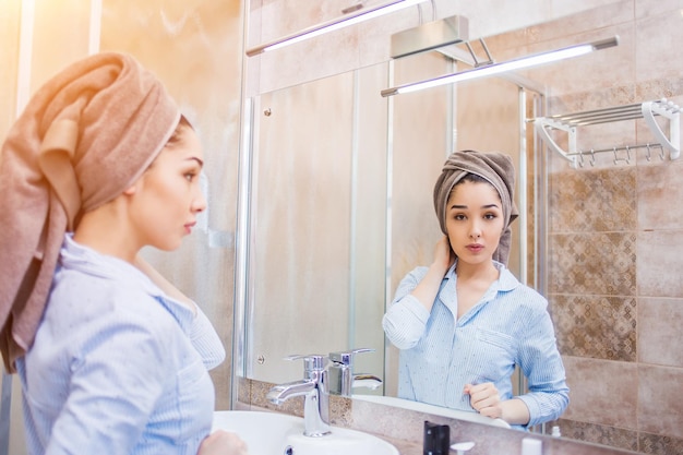 Beautiful woman with a towel on her head standing in bathroom after shower.