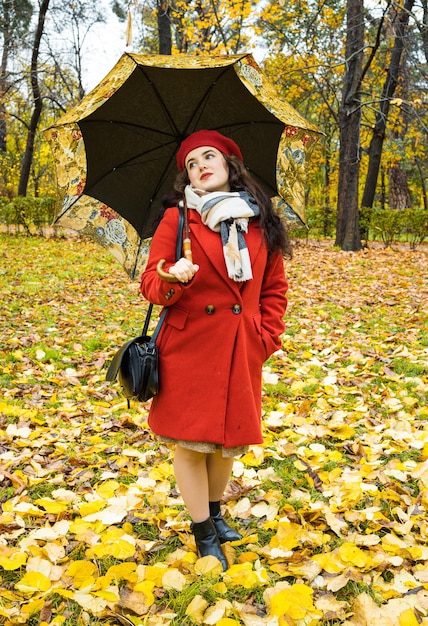 Foto bella donna con un ombrello nel parco autunnale