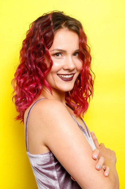 Photo beautiful woman with wavy red hair on yellow background