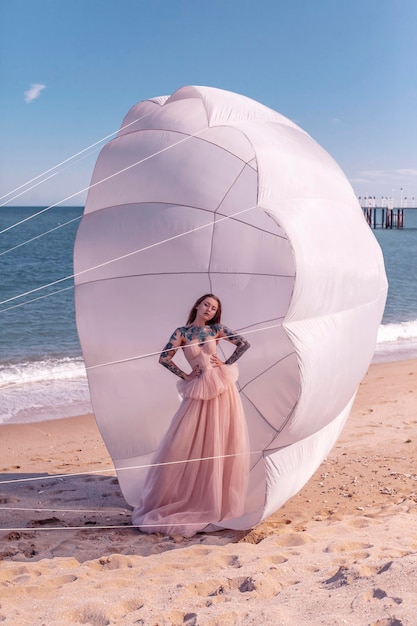 Beautiful woman with white parachute at the beach