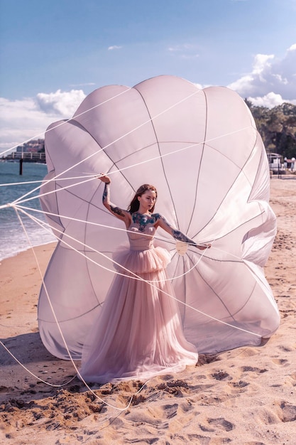 Photo beautiful woman with white parachute at the beach