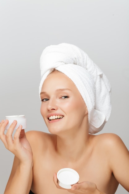 Beautiful woman with a white towel and a cream jar