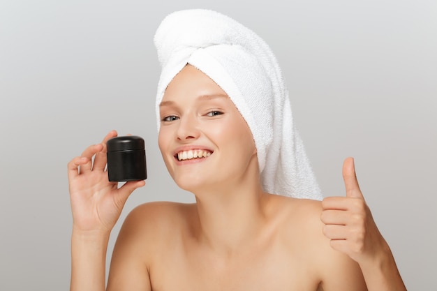 Beautiful woman with a white towel and a cream jar