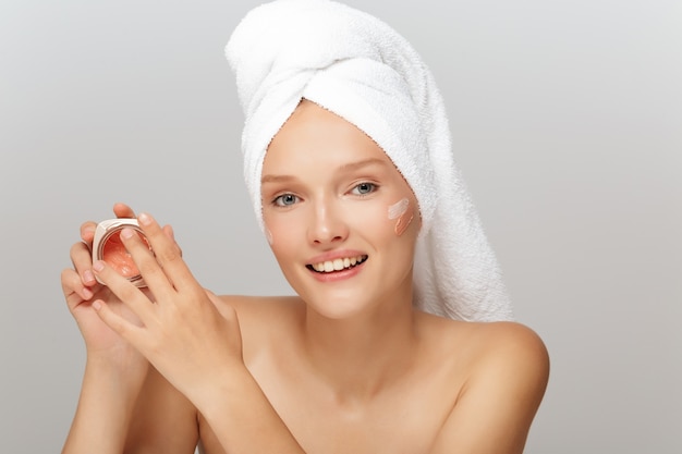 Beautiful woman with a white towel and a cream jar