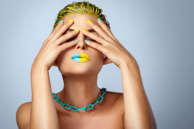 Bella donna con i capelli gialli e unghie e labbra colorate