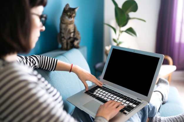 自宅でラップトップに取り組んでいる美しい女性。ノートパソコンの黒い画面。テクノロジー、フリーランス。