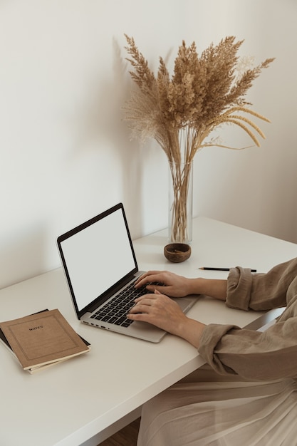 Bella donna che lavora, digitando sul computer portatile. design degli interni dell'area di lavoro dell'home office accogliente e confortevole