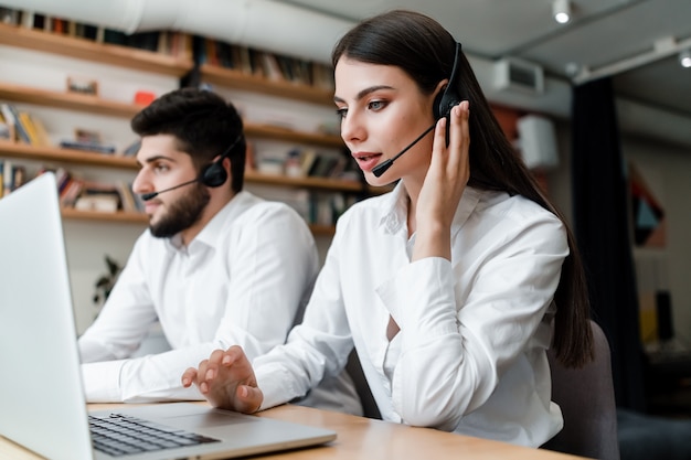 Photo beautiful woman works in call center with headset answering client phone calls