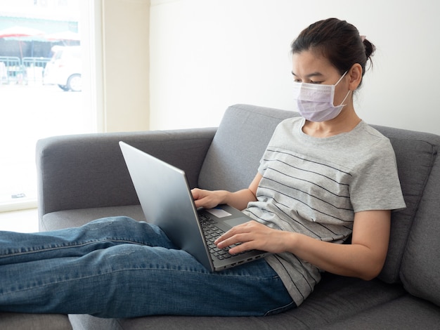 La bella donna lavora a casa sul suo computer portatile