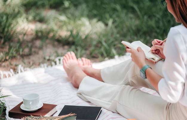 Beautiful woman writing on diary in the park.