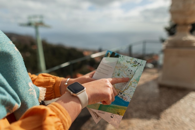 Красивая женщина в желтом платье и шарфе путешествует с картой и указывает пальцем на остров Мадейра Португалия