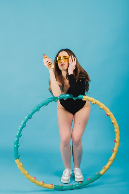 beautiful woman in yellow glasses with a hula hoop holds a hot dog in her hand