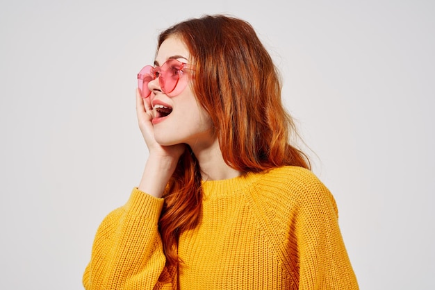 Beautiful woman in a yellow sweater hairstyle fashion glasses light background