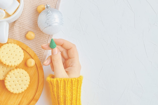 Beautiful woman in yellow sweater holding miniature Christmas tree with ornaments