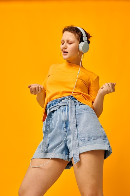 Beautiful woman yellow tshirt headphones entertainment music fun isolated backgrounds unaltered