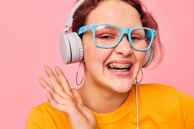 Beautiful woman yellow tshirt headphones entertainment music fun pink background unaltered