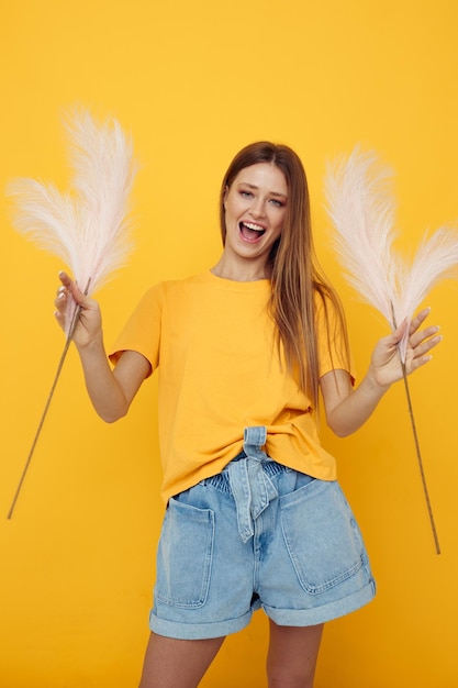 黄色のTシャツピンクの羽の孤立した背景の美しい女性