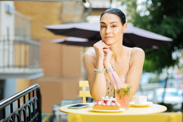 きれいな女性。彼女の前においしいデザートと落ち着いてカフェのテーブルに座っている若い美しい女性