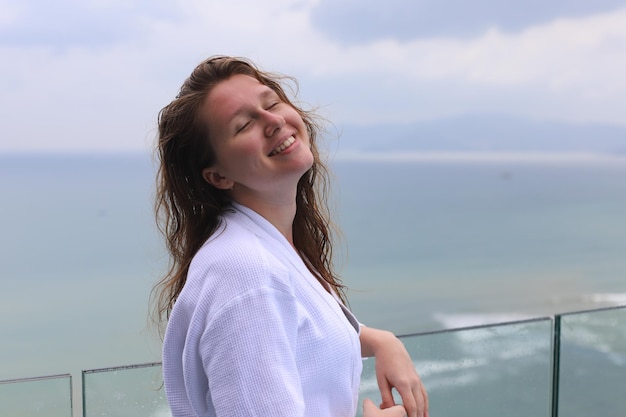 Beautiful woman young girl in a white bathrobe in a spa luxury hotel on the rooftop with sea or