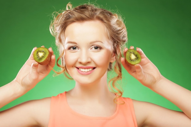 Beautiful womans face with kiwi over green background