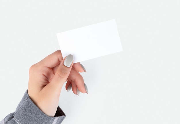 Beautiful womans hand with manicure holding business card