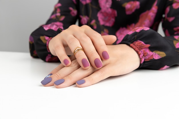 Beautiful womans hands with purple burgundy matte manicure.