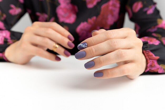 Mani di bella donna con manicure opaca bordeaux viola.