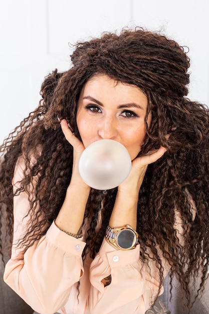 Beautiful women blowing bubble from chewing gum and looking into the camera