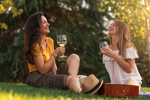 公園でワインを飲む美しい女性。友達と夏のコンセプト。