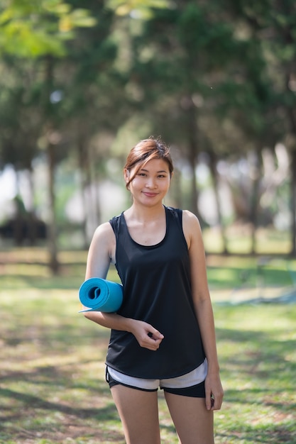 Beautiful women holding yoga mat prepare to exercise yoga in the garden