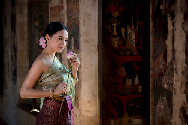 Фото Девушка красивых женщин тайская держа лотос руки в традиционном тайском костюме с ayutthaya виска.