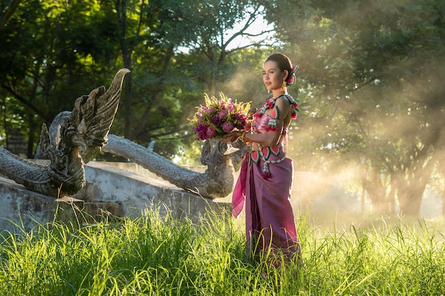 Beautiful women Thai girl holding hand lotus in traditional thai costume with temple ayutthaya, identity culture of Thailand .