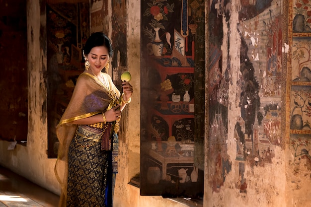 Beautiful women Thai girl holding hand lotus in traditional thai costume with temple ayutthaya.