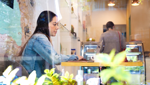 写真 コーヒーショップでラップトップを使用して美しい女性