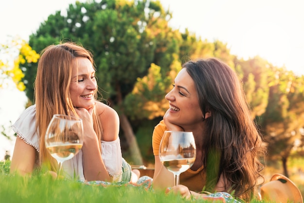 Beautiful women using mobile in the park. Friends and summer concept.