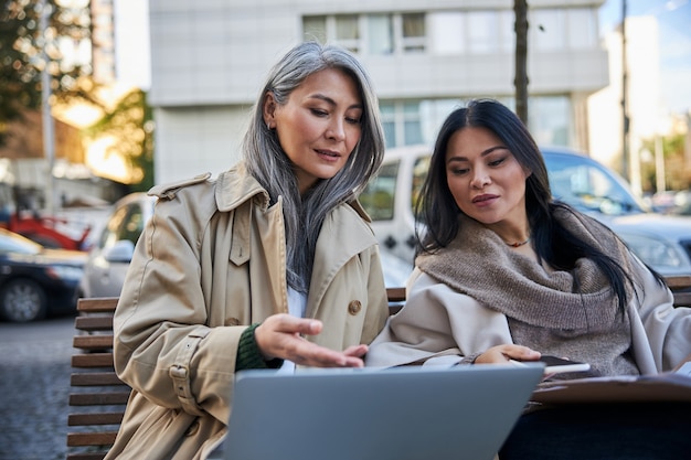 Beautiful women using modern notebook on the street