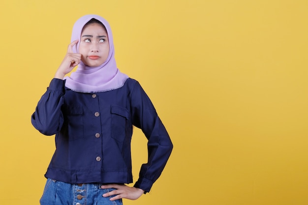 Belle donne che indossano hijab e abiti casual che fanno seriamente supposizioni, guardano bene e pensano sullo sfondo giallo