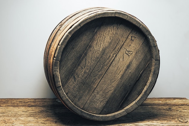 Foto bellissimo barile di legno su un vecchio tavolo di legno di quercia sullo sfondo bianco della parete