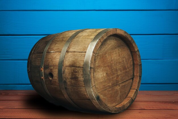 Beautiful wooden barrel on a red wood table and blue wood wall background